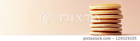 A stack of pancakes is neatly piled on a flat surface with a plain background. Concept of breakfast, simplicity, and minimalism. For food advertisement. 129329105