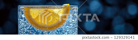 A slice of orange submerged in a fizzy drink in a glass with bubbles visible. Concept of refreshing citrus beverage. For drink advertisement. 129329141