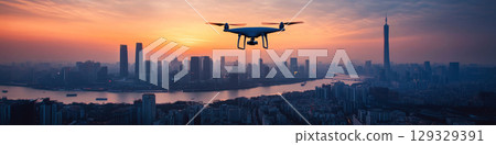 A drone hovers over a cityscape at sunset, silhouetted against the vibrant sky. Concept of technology and urban exploration. For technology promotion A drone hovers over a cityscape at sunset, silhouetted against the vibrant sky. Concept of technology and urban exploration. For technology promotion 129329391