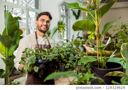 Handsome young man with plenty green plants in the flower shop 129329629