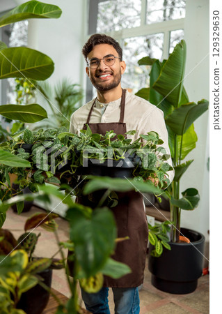 Handsome young man with plenty green plants in the flower shop 129329630