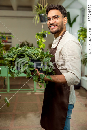 Handsome young man with plenty green plants in the flower shop 129329632