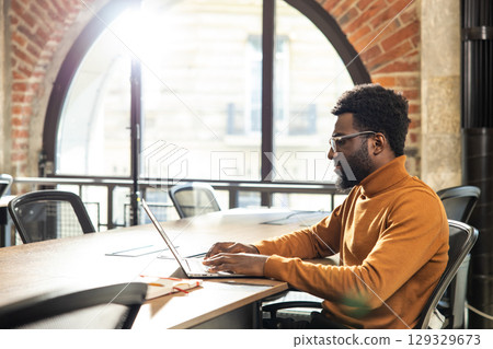 African American male professional working remotely using laptop in bright coworking space African American male professional working remotely using laptop in bright coworking space 129329673