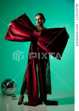 Woman Holding Giant Red Bow in Stylish Setting Woman Holding Giant Red Bow in Stylish Setting 129329796