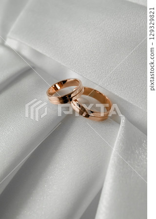 Two Gold Wedding Rings on White Fabric Background Two Gold Wedding Rings on White Fabric Background 129329821