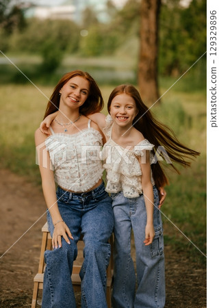 Happy Sisters Smiling Outdoors on a Sunny Day 129329896
