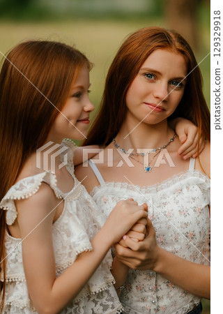 Sisters Holding Hands in a Tender Moment Outdoors 129329918
