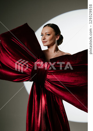 Elegant Woman Posing with Large Red Wrapped Bow 129329938