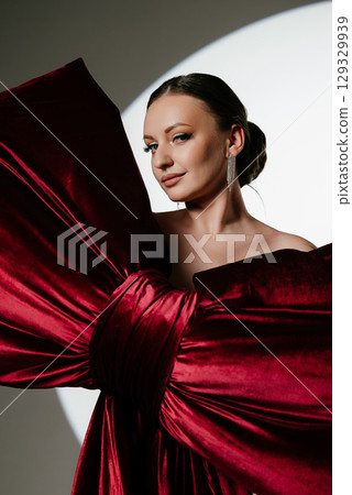 Elegant Woman Wrapped in Large Red Velvet Bow 129329939