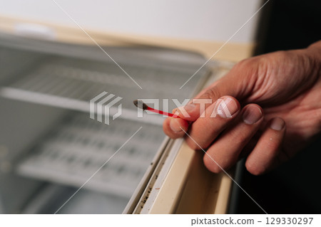 Close-up of housekeeper cleaning refrigerator door rubber seal with cotton swab, focusing on thorough sanitation and tight sealing, closeup. Concept of hygiene and cleanliness in domestic environment Close-up of housekeeper cleaning refrigerator door rubber seal with cotton swab, focusing on thorough sanitation and tight sealing, closeup. Concept of hygiene and cleanliness in domestic environment 129330297