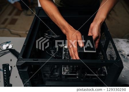 Close-up cropped shot of technician installing CPU water cooler into desktop computer case, showcasing process of computer maintenance and upgrade. Concept of desktop PC maintenance and service. 129330298