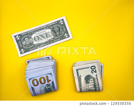 1 dollar against a stack of dollars, trade war tariffs, on a yellow background, top view 1 dollar against a stack of dollars, trade war tariffs, on a yellow background, top view 129330350