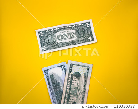One dollar and a couple of dollar bills, on a yellow background, in the center of the image, top view 129330358