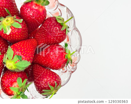 Fresh strawberries in transparent glass bowl flat lay. Healthy food on light pink table mock up. Delicious, sweet, juicy and ripe berry background with copy space for text Fresh strawberries in transparent glass bowl flat lay. Healthy food on light pink table mock up. Delicious, sweet, juicy and ripe berry background with copy space for text 129330363
