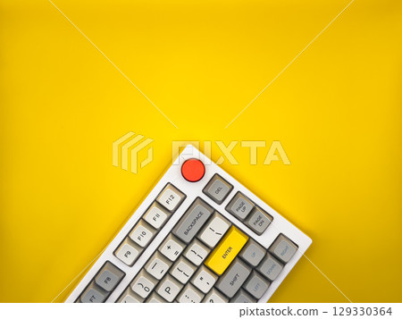 Workspace desk with it keyboard, red and yellow buttons, with yellow background. Flat lay. Top view, copy space. 129330364