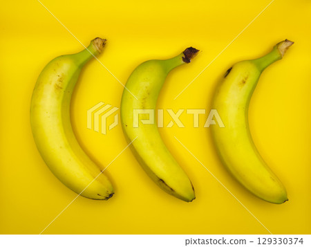 Colorful fruit pattern of fresh yellow bananas on yellow background. From top view Colorful fruit pattern of fresh yellow bananas on yellow background. From top view 129330374
