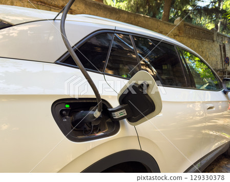Concept of electric car charging the battery in a city charging station. 129330378