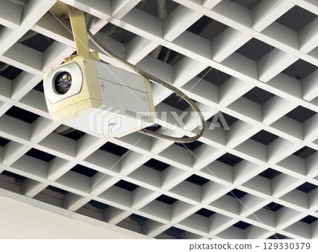 A security camera on the ceiling follows every step of a person 129330379