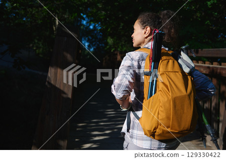 Hiker Crossing Wooden Bridge in Nature with Backpack and Trekking Gear 129330422