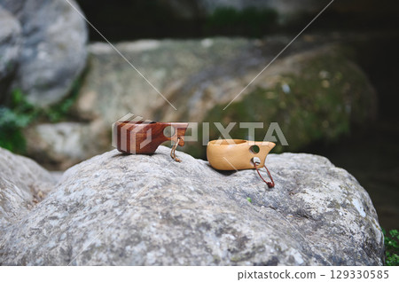 Close-Up of Wooden Kuksa Cups on Rocks in a Tranquil Natural Setting Close-Up of Wooden Kuksa Cups on Rocks in a Tranquil Natural Setting 129330585