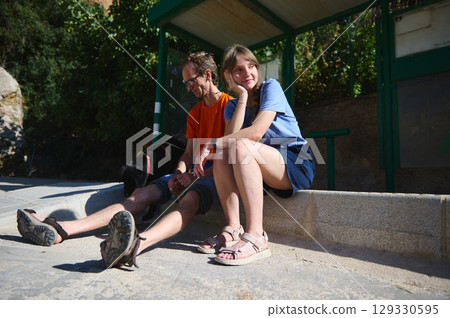 Casual Moment of Two Friends Sitting at a Bus Stop with a Dog Casual Moment of Two Friends Sitting at a Bus Stop with a Dog 129330595