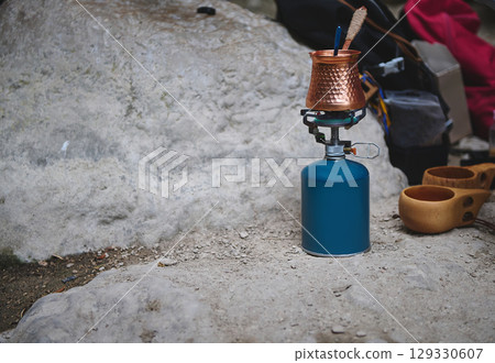 Portable Gas Stove Setup with Copper Pot on Outdoor Rock Surface 129330607