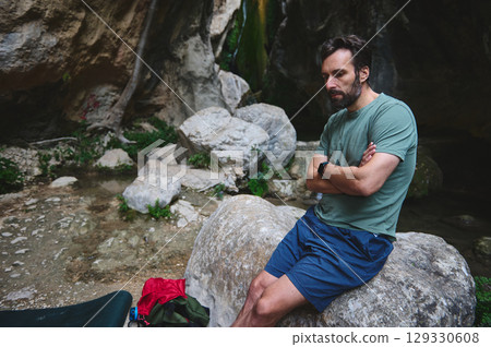 Man Sitting Thoughtfully in a Scenic Outdoor Rocky Setting Man Sitting Thoughtfully in a Scenic Outdoor Rocky Setting 129330608