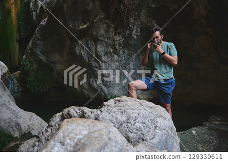 Man Enjoying a Refreshing Moment Near a Rocky Waterfall Scene 129330611