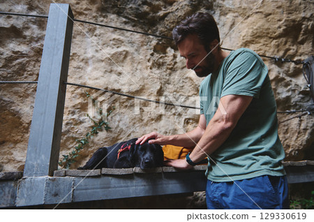 Man Caring for His Dog in a Scenic Outdoor Rocky Setting 129330619