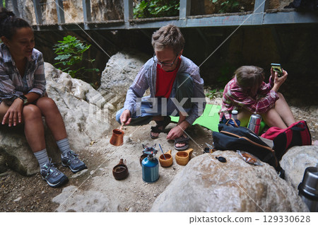 Group of Campers Preparing Coffee Outdoors in a Natural Setting Group of Campers Preparing Coffee Outdoors in a Natural Setting 129330628
