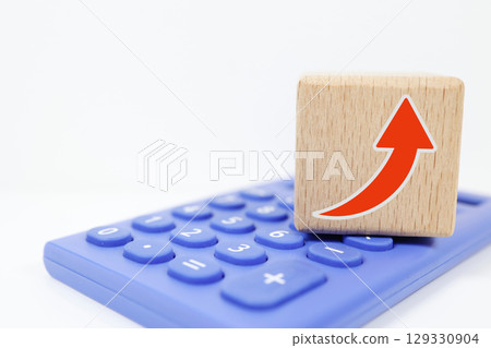 計算器頂部放置一個帶有向上箭頭的木塊 129330904