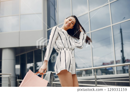 Beautiful girl in a summer city. Lady with shopping bags 129331159