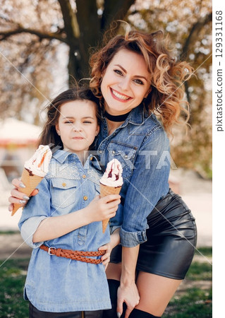 Fashionable mother with daughter. Family in a spring park. Woman in a blue shirt 129331168