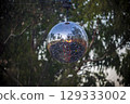 View of a disco ball hanging on a festival stage located in a forest 129333002