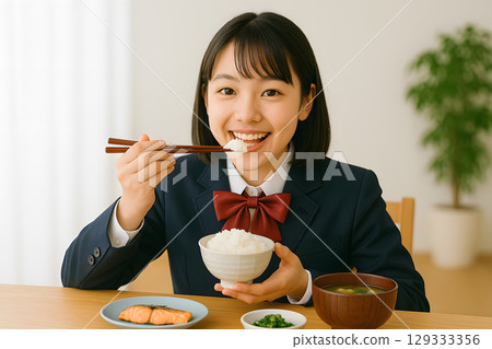 A female student eating white rice. Portrait of a smiling student having breakfast. Copy space available 129333356