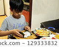 Elementary school child making hand-rolled sushi for dinner 129333832