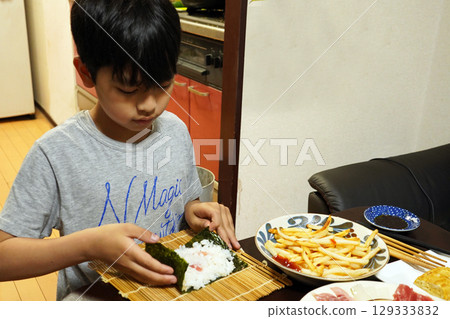 Elementary school child making hand-rolled sushi for dinner 129333832