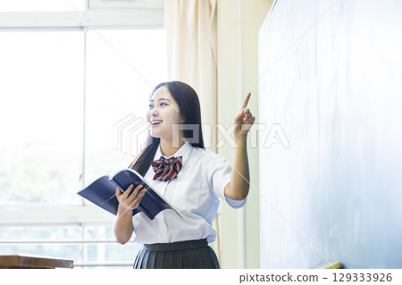 High school girl making a presentation in front of the blackboard High school girl making a presentation in front of the blackboard 129333926