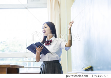 High school girl making a presentation in front of the blackboard High school girl making a presentation in front of the blackboard 129333928