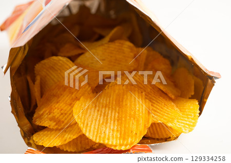Potato chips, delicious BBQ seasoning spicy for crips, thin slice deep fried snack fast food in open bag. Potato chips, delicious BBQ seasoning spicy for crips, thin slice deep fried snack fast food in open bag. 129334258