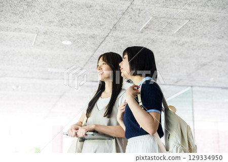 兩名背著背包的女學生在校園裡微笑交談 129334950