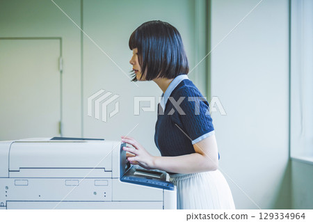 A woman operating a copy machine A woman operating a copy machine 129334964