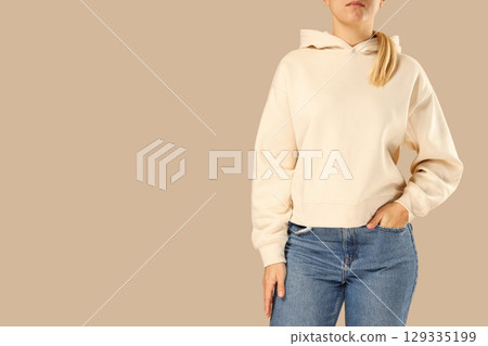 Model in beige hoodie and jeans on neutral backdrop Model in beige hoodie and jeans on neutral backdrop 129335199