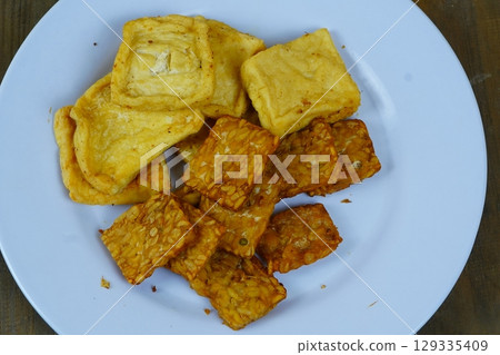 A plate of Indonesian fried snacks, including golden-brown fried tofu and crispy fried tempeh, showcasing the popular local side dishes. 129335409