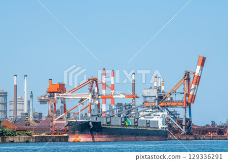 A large transport ship and gantry crane docking at the quay of the industrial complex A large transport ship and gantry crane docking at the quay of the industrial complex 129336291