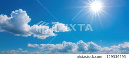 Bright Blue Sky with Fluffy Clouds and Glowing Sunlight 129336393