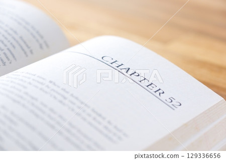 一張圖片：某人在打開英文平裝書時放鬆並享受閱讀的樂趣。 129336656