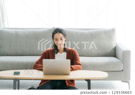 在客廳裡操作個人電腦的女人 129336665