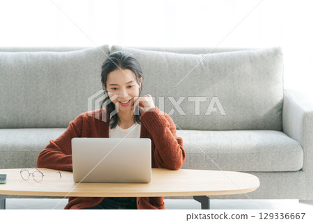 在客廳裡操作個人電腦的女人 在客廳裡操作個人電腦的女人 129336667