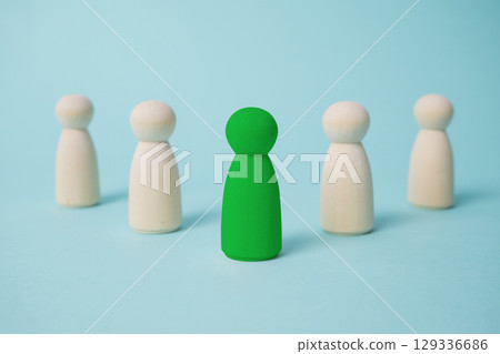 Green leads others from other wooden dolls on blue background. 129336686